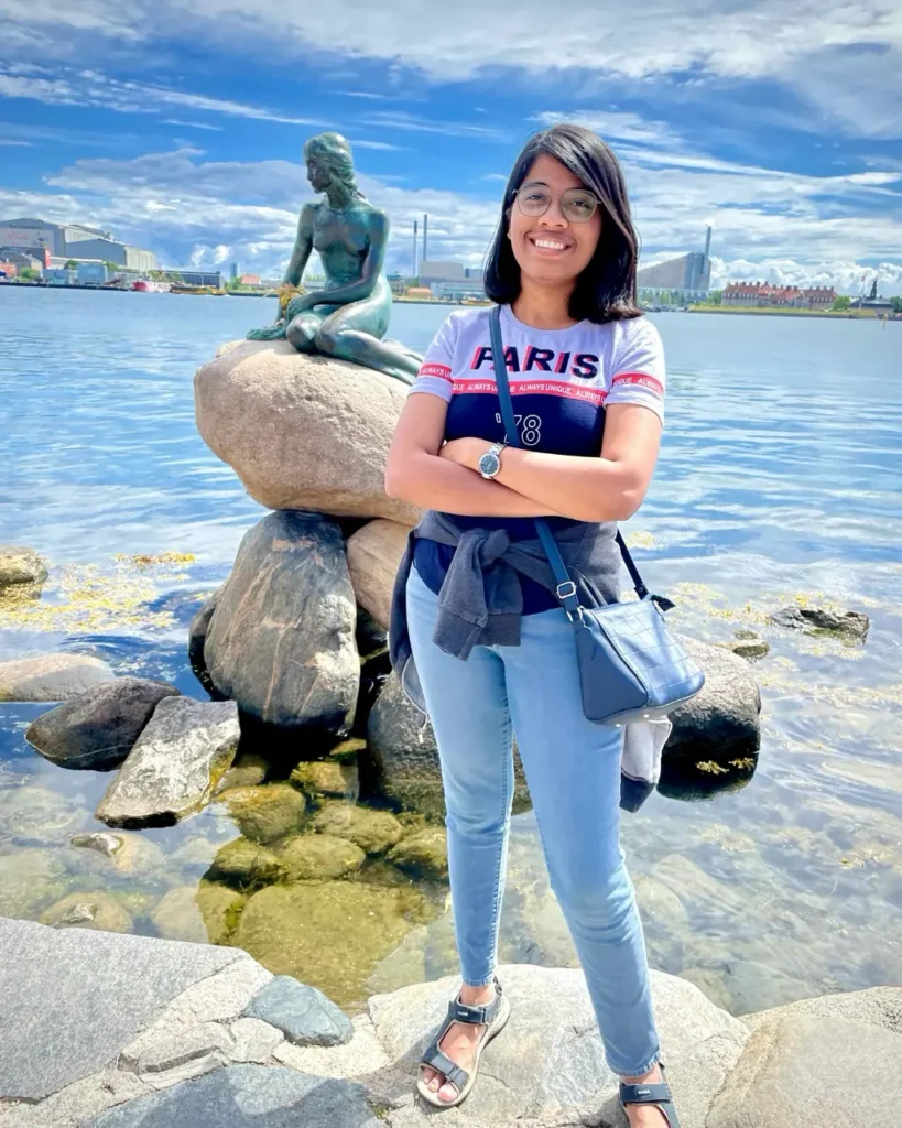 Agalya standing with the little mermaid statue in Copenhagen