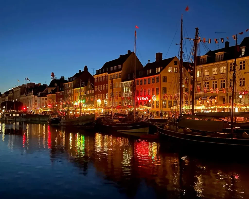 Nyhavn at night with colorful buildings reflecting on the water