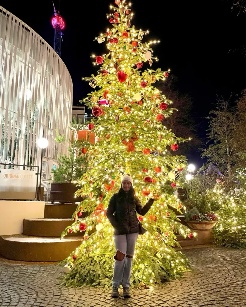 Agalya standing in front of the Tivoli gardens Christmas tree decorations in the amusement park