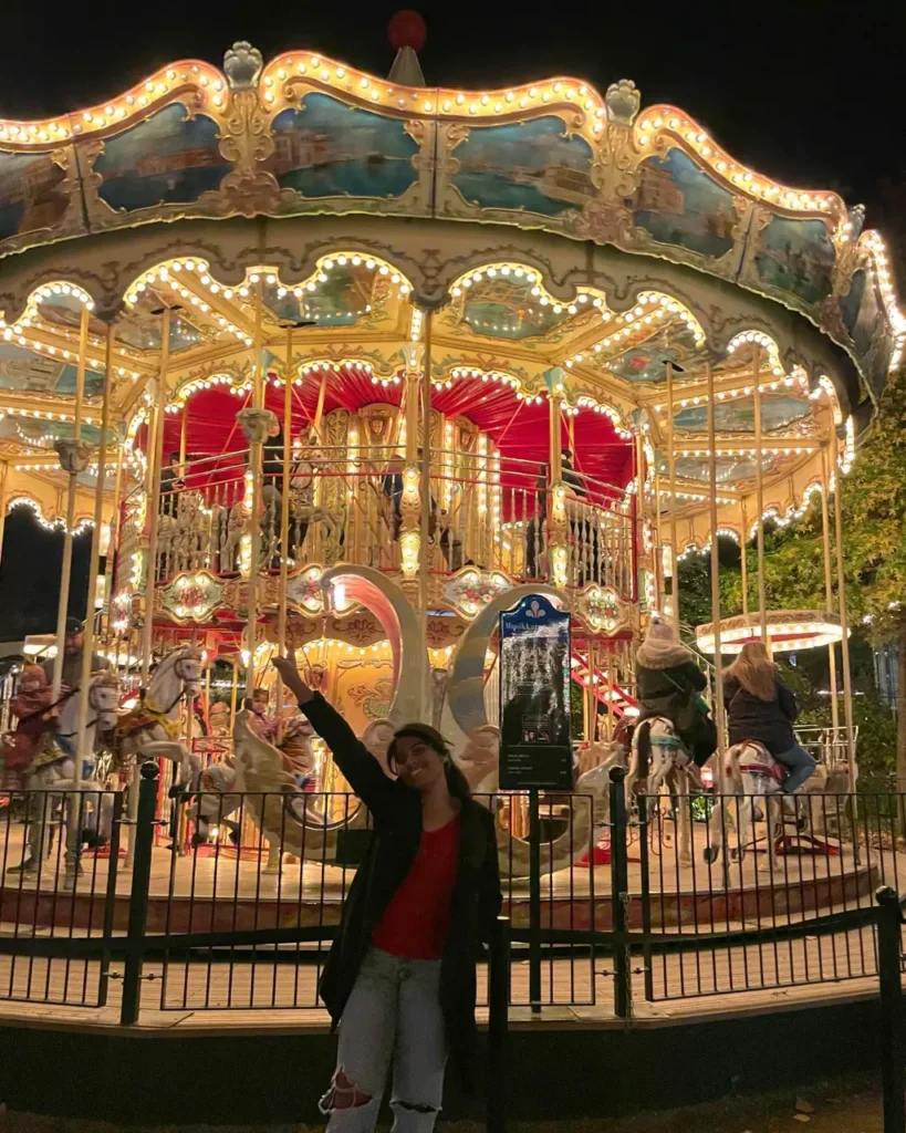 Agalya standing infront of Tivoli Gardens carousel ride at night